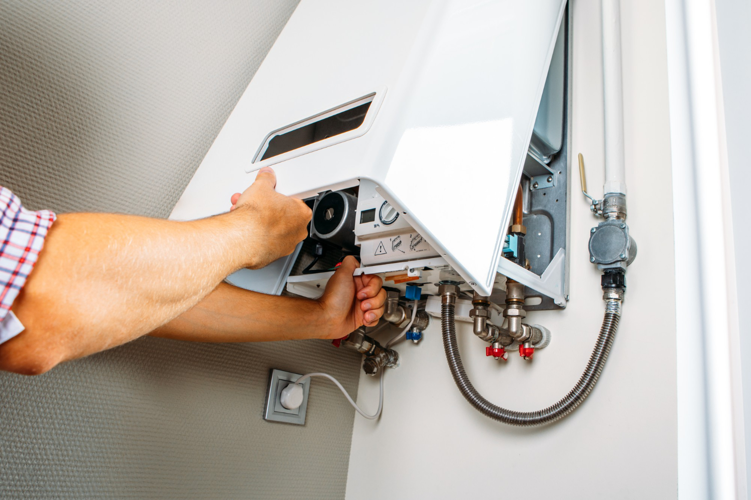 HVAC Blog 6 Person servicing a tankless water heater, adjusting components and controls, relevant to HVAC maintenance tips.